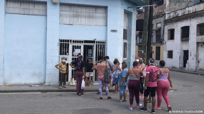 A line of a dozen people in front of a Cuban store