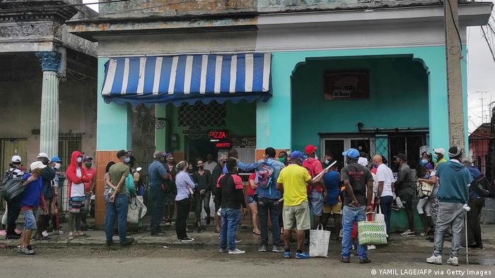 People wearing face masks line up to buy food in Havana