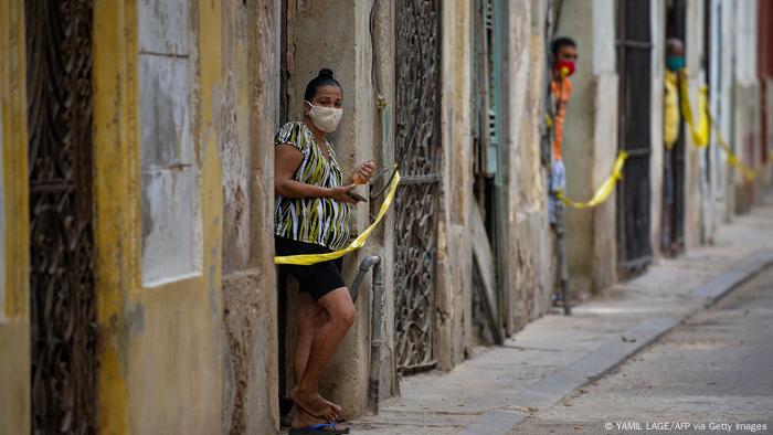 People stand at the door of their houses that were cordoned off amid quarantine measures in a restricted area of Havana
