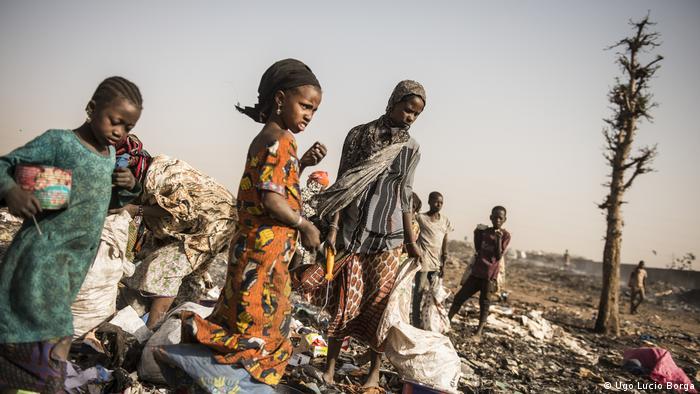 Malian refugees, including women and children, walk with their belongings