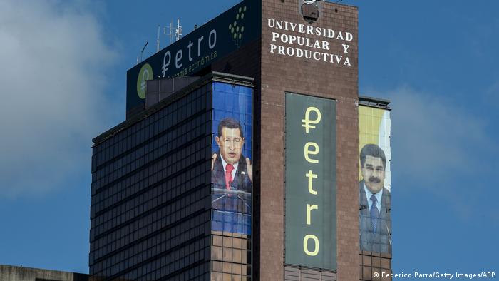 The logo of the Petro is displayed next to images of Venezuelan late President Hugo Chavez and Venezuelan President Nicolas Maduro in a building in downtown Caracas