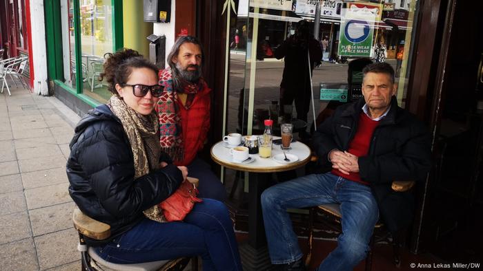 Mulher e dois homens em mesa de café de rua