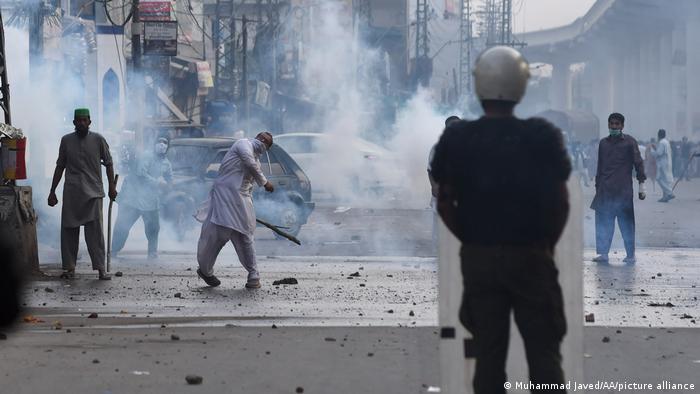 Pakistani Islamists of Tehreek-e-Labbaik Pakistan (TLP) throw stones against police who use teargas against anti-France Islamist protesters during a protest in Lahore, on April 12, 2021