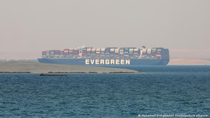 Distant photo of the Ever Given, stacked with containers, in lake waters surrounded by desert