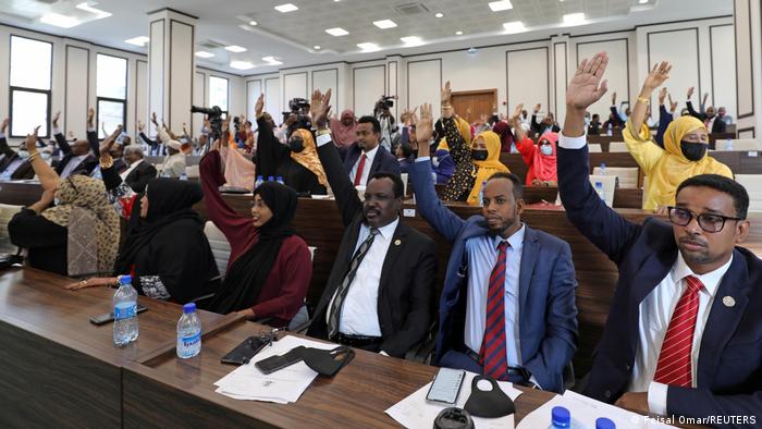 Somali legislators of the lower house of parliament raise their hands to vote