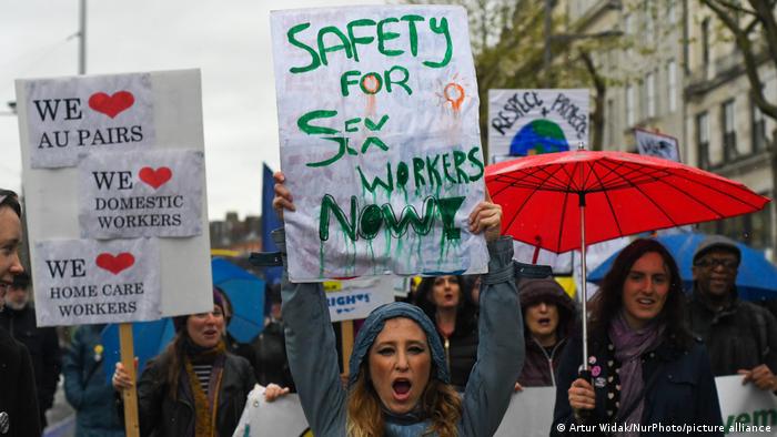  A young woman holds 'Safety for Sex Workers Now!' sign during an annual May Day march for workers' rights