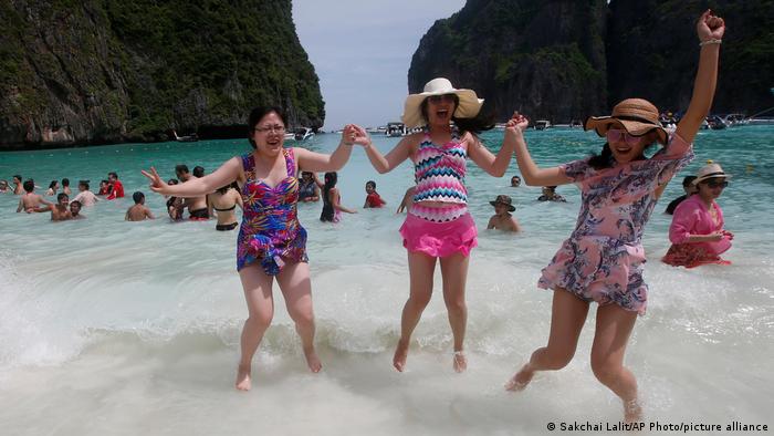 Three women jump in the waves at Maya Bay as they pose for a photo