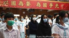 Students wearing face masks stand and watch, while standing under a banner with patriotic slogans, during a flag raising ceremony on the National Security Education Day, in a Secondary School in Hong Kong, China on 15 April, 2021. Hong Kong will host for the first time a National Security Education Day Today, This comes after the implementation of the national security law last year, Over 100 people have been arrested under the national security law, with prominent Pro-Democracy Figures, like Jimmy Lai who has been charged with the law , and the arrest of over 47 People who participated in last years pro-democracy primary election. (Photo by Vernon Yuen/NurPhoto)