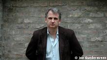 Timothy Snyder in front of a greyish brick wall