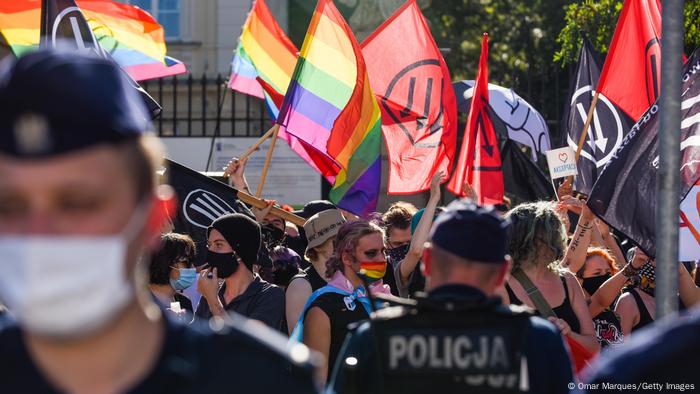 LGBT+ activists hold banners and rainbow flags during a protest