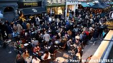 People sit at the terrace of a bar, as the coronavirus disease (COVID-19) restrictions ease, in Soho, London, Britain, April 16, 2021. REUTERS/Henry Nicholls