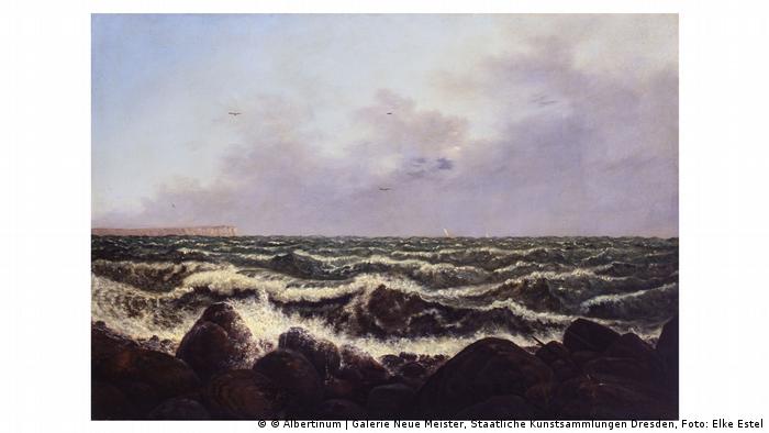 Das Gemälde Brandung auf Rügen gibt den Blick auf aufgewühltes Meer frei. In der Ferne tauchen am Horizont links die berühmten Kreidefelsen der Ostseeinsel auf.