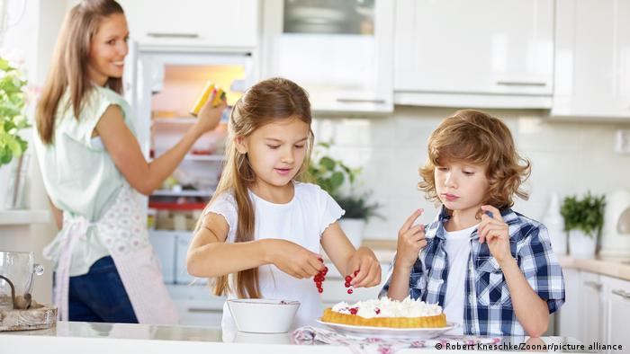Хлопчик і дівчинка допомагають мамі прикрасити торт