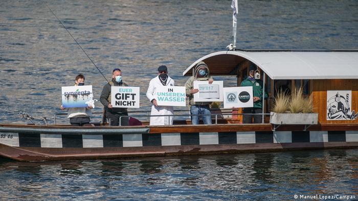 People on a boat hold up signs against pesticides