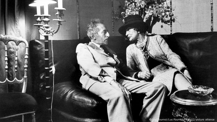 Writer Jean Cocteau and fashion designer Coco Chanel on a dark leather sofa.