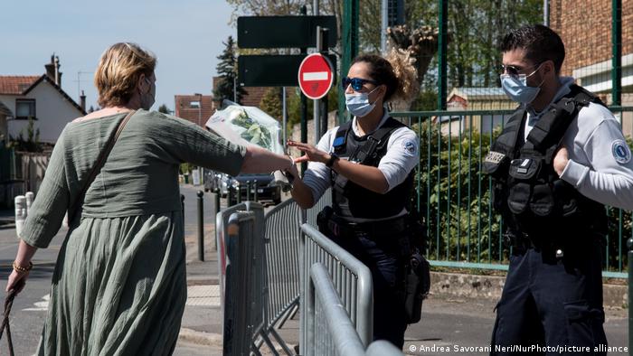 Un policía recibe un ramo de flores de una mujer que rinde homenaje al policía muerto en un atentado en la comisaría de Rambouillet.