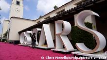 24.04.2021, USA, Los Angeles: Ein Mitglied der Academy Awards-Crew begutachtet auf dem roten Teppich in der Union Station, einer der Locations für die 93. Academy Awards, ein Hintergrundelement, das das Wort OSCARS formt. Foto: Chris Pizzello/AP/dpa +++ dpa-Bildfunk +++