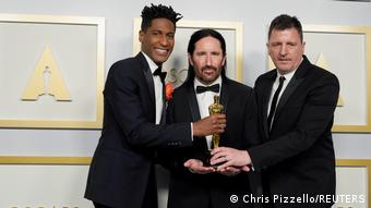 Jon Batiste, Trent Reznor and Atticus Ross holding the Oscar for best score.