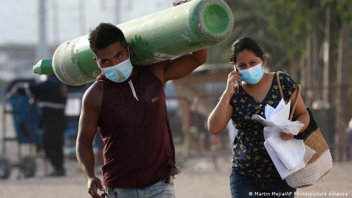 Familiares de un paciente de COVID-19 cargan con oxígeno en un barrio de Lima, Perú