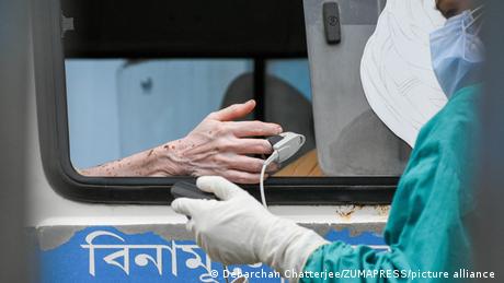 A health worker tests blood oxygent level of a patient inside an ambulance who tested positive for COVID-19 at a hospital in Kolkata, India