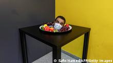 TOPSHOT - A visitor peeks out of a bowl of fruit, part of an optical illusion installation, at the Illusion Museum in Arbil, the capital of Iraq's northern autonomous Kurdish region, on April 26, 2021. (Photo by SAFIN HAMED / AFP) (Photo by SAFIN HAMED/AFP via Getty Images)