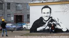 ST PETERSBURG, RUSSIA - APRIL 28, 2021: A man poses for a photograph by a mural depicting Russian opposition activist Alexei Navalny and reading The hero of new times on a transformer house in Pushkarsky Garden. The mural was discovered in the early morning of April 28 and painted over around 10:30 am. Alexander Demianchuk/TASS