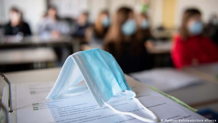 students in a classroom, a covid mask on a desk 