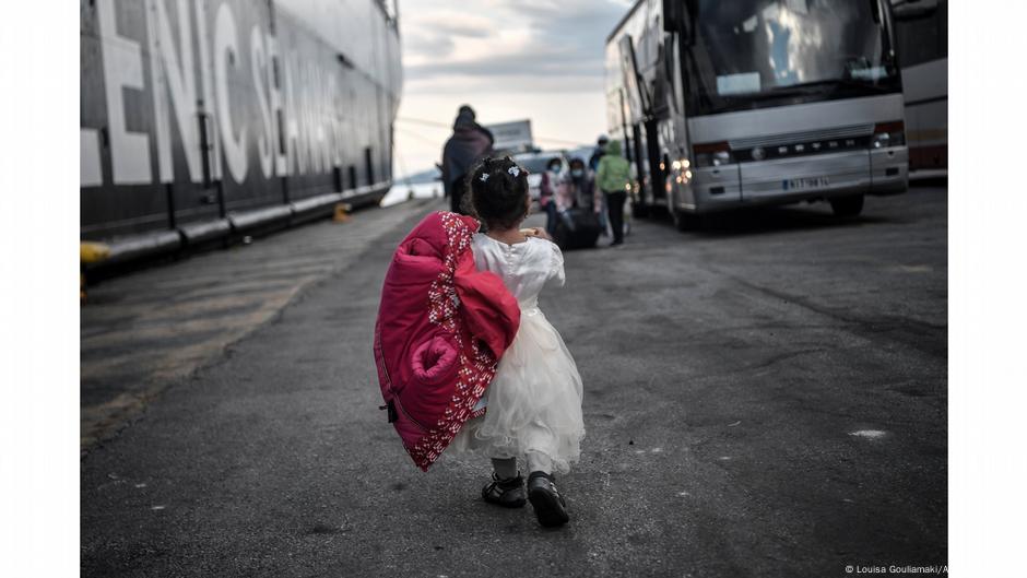 Little girl seen from back walking to a bus at a port. Photo: Louisa Gouliamaki, Lesbos, Greece