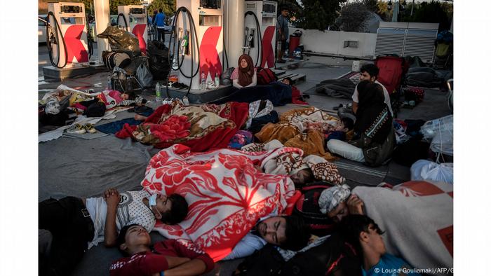 Refugiados desabrigados dormem em seus cobertores na área de um posto de gasolina na Grécia