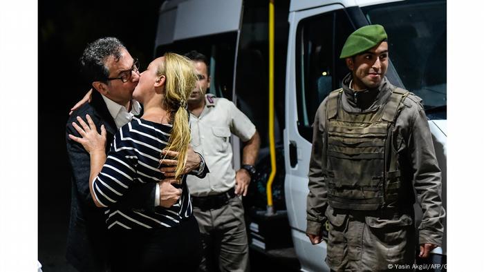 Jornalista recém-libertado da prisão, Kadri Gürsel beija sua esposa ao lado de dois guardas e uma van, na Turquia