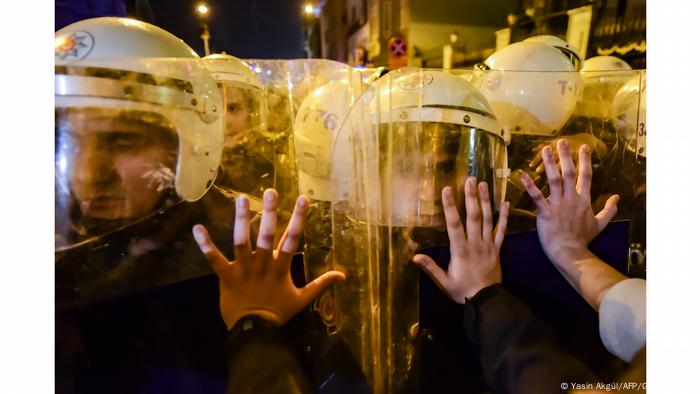 Mãos de manifestantes tocam escudos de policiais nas ruas da Turquia