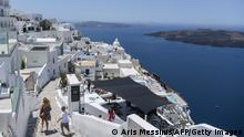 People walk in the empty alleys in the town of Fyra in the island of Santorini on June 14, 2020 as the country prepares for the return of tourists to Greece from around 30 countries by air, sea and land. - From the emblematic island of Santorini, Greek Prime Minister said on June 13 that Greece is ready to welcome tourists in complete safety after the coronavirus lockdown, whose impact on tourism will be significant. With its postcard landscape splashed with sunshine, the island of Santorini, one of the most touristic in Greece, awaits the return of tourists on June 15, divided between impatience to revive its effervescence and fear of seeing the coronavirus emerge from which it had so far been preserved. (Photo by ARIS MESSINIS / AFP) (Photo by ARIS MESSINIS/AFP via Getty Images)