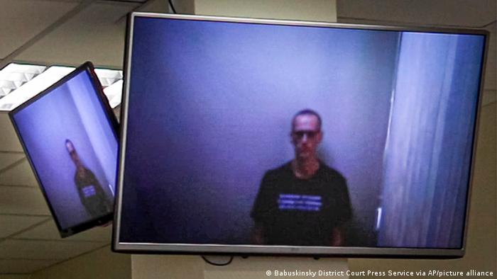 Russian opposition leader Alexei Navalny appears on TV screens via a video link from prison