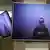 Duas televisões penduradas transmitem a imagem de Navalny. Ele está com uma camiseta preta.
