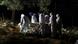 Gravediggers wearing protective suits carry a coffin as spotlights illuminate the graves during a night burial at Vila Formosa cemetery. Gravediggers wearing protective suits carry a coffin as spotlights illuminate the graves during a night burial at Vila Formosa cemetery.