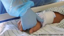 TOPSHOT - A doctor holds the hand of a Covid-19 patient in the Covid-19 intensive care unit of the community hospital (Klinikum Magdeburg) in Magdeburg, eastern Germany, on April 28, 2021, amid the novel coronavirus COVID-19 pandemic. (Photo by Ronny Hartmann / AFP)