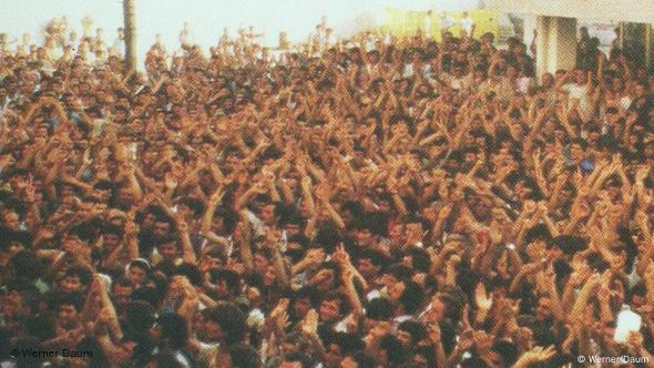 Mbi 3000 shqiptarë të strehuar në korrik 1990 në mjediset e Ambasadës së Republikës Federale të Gjermanisë duke brohoritur pas marrjes së lajmit për largimin nga Shqipëria dhe udhëtimin drejt Gjermanisë.