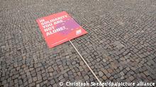 Ein Schild mit der Aufschrift «Solidarisch ist man nicht alleine!» in englischer Sprache liegt bei einer Bild-Aktion des Deutschen Gewerkschaftsbundes (DGB) zum Tag der Arbeit vor dem Brandenburger Tor. Mit der Aktion präsentiert der DGB sein Motto zum 1. Mai „Solidarisch ist man nicht alleine“.