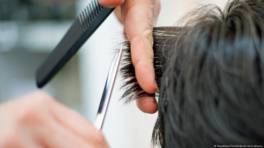 Ein Friseur schneidet einer Kundin mit einer Schere die Haare. Zu sehen sind zwei Hände und die nassen Haare, eine Schere und ein Kamm. Ein Friseur schneidet einer Kundin mit einer Schere die Haare. Zu sehen sind zwei Hände und die nassen Haare, eine Schere und ein Kamm.