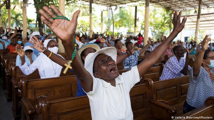 A man raises his arms during a Catholic mass in Port-au-Prince, Haiti