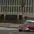 The US Embassy in Havana with an old car driving in front 