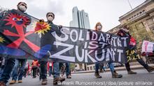 An der Zentrale der Deutschen Bank (hinten) vorbei ziehen Menschen mit einen Transparent mit dem Motto «Solidarität ist Zukunft» zum Opernplatz bei einer Demonstration, zu der der Deutsche Gewerkschaftsbund am Tag der Arbeit aufgerufen hatte. Mit Mindestabständen und der Pflicht zum Maske-Tragen sollte für größtmögliche Sicherheit gesorgt werden.