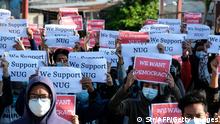 People hold signs reading 'we support NUG'
