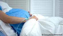 Pregnant woman holding blanket, feeling abdominal pain, risk of miscarriage