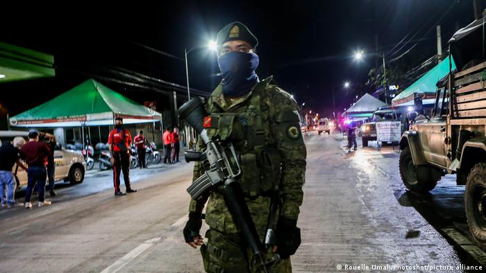 Nighttime, armed and masked soldier in Valenzuela City looks into the camera