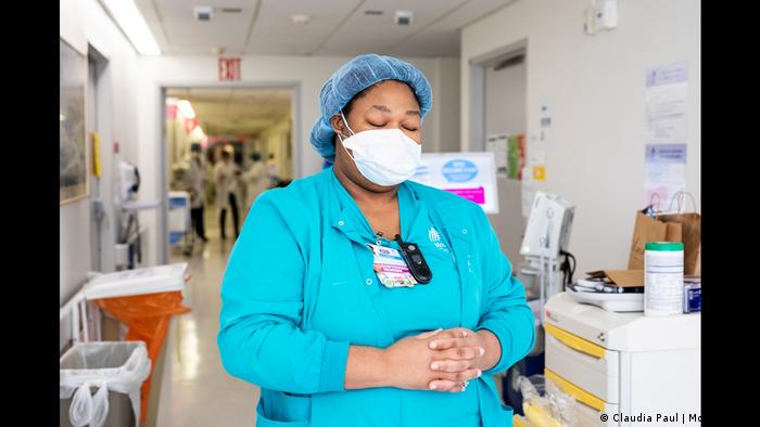 Fotoreihe Faces of Resilience: eine Krankenschwester betet mit geschlossenen Augen im Krankenhausflur