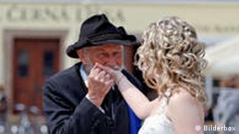 Ein älterer Mann gibt einer Braut einen Handkuss