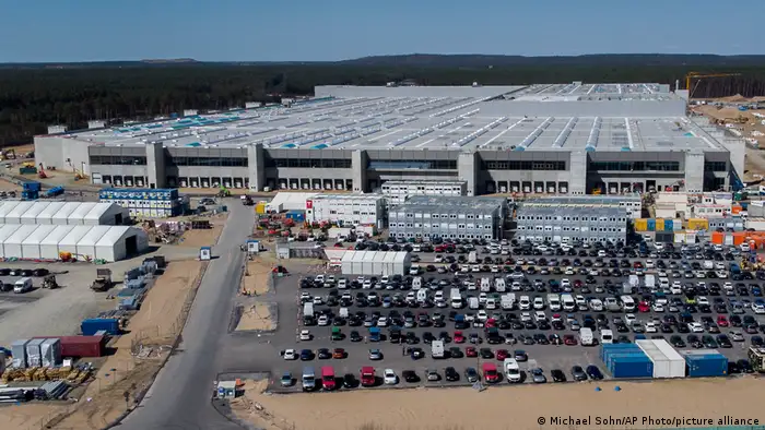 Tesla Gigafactory near Berlin with dozens of cars parked outside and grey concrete roof
