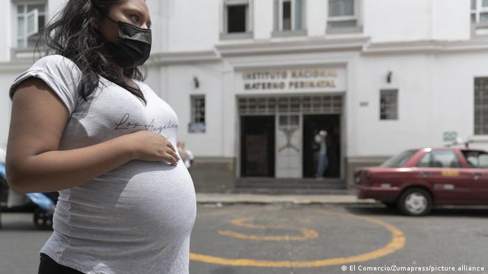 Eine Schwangere steht mit Maske vor einem Krankenhaus in Peru