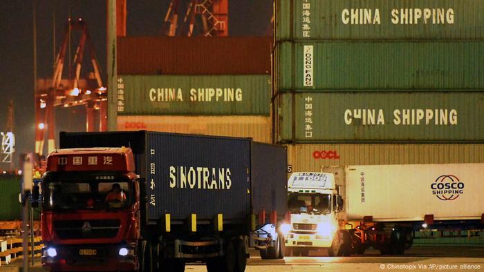 Shipping containers with China Shipping logo and trucks in a Chinese dockyard